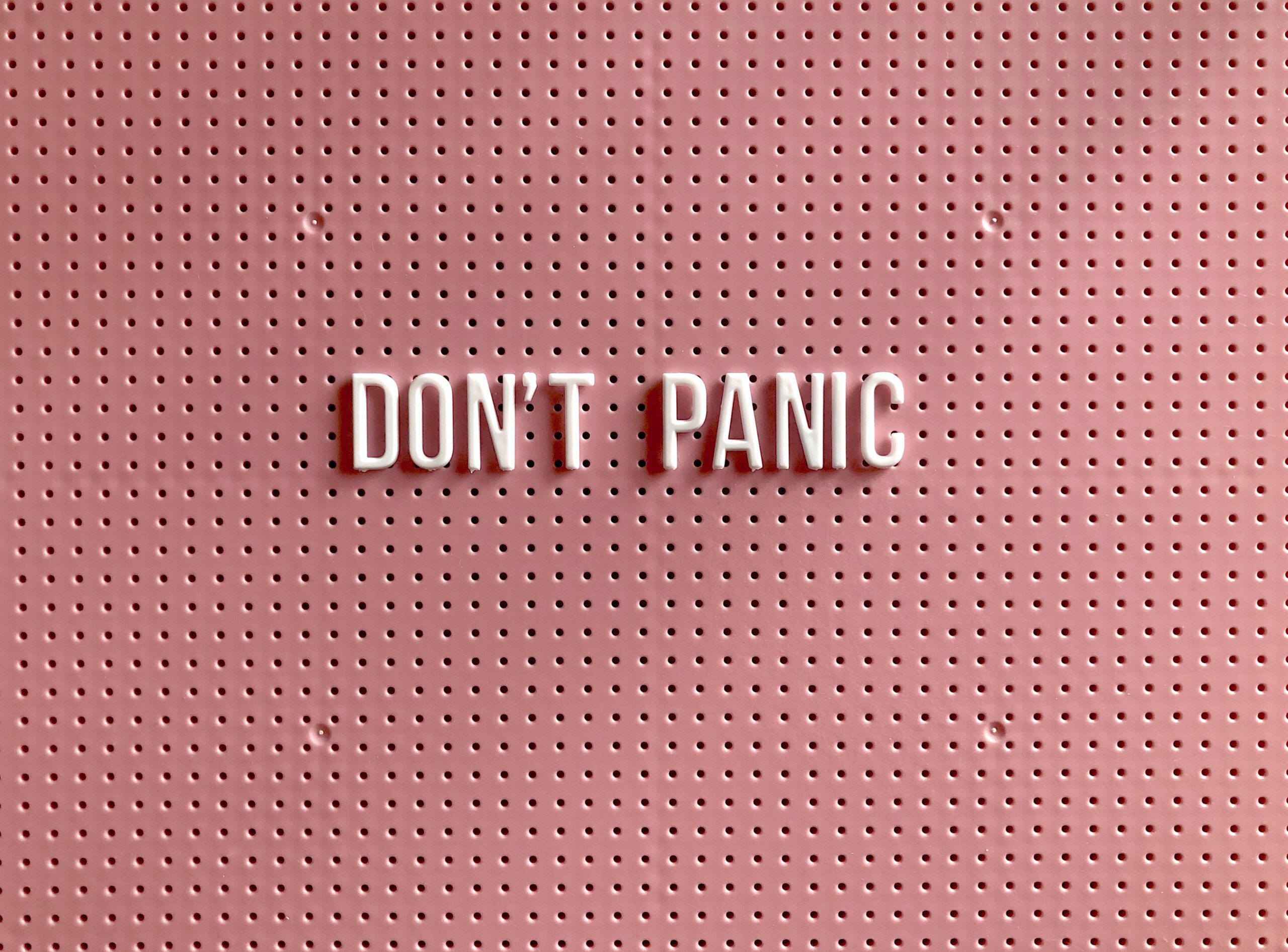Blog about the current Durham real estate market. Pink board that says Don't Panic. Featured Image for regular blog post